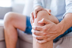 Mann hält sich schmerzendes Knie